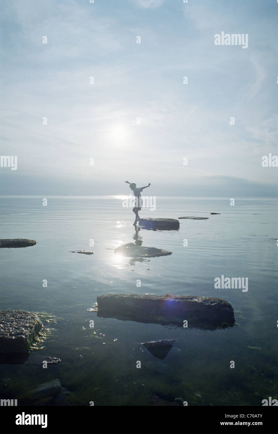 Donna che gioca sulle rocce nel lago Foto Stock