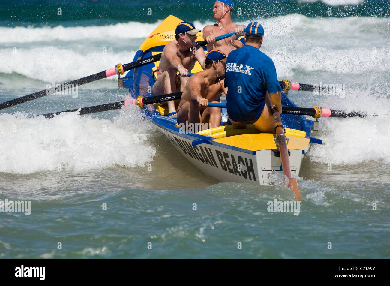 L'equipaggio della Bungan Beach surf barca di salvataggio di affrontare la prima delle forme d'onda all'inizio di una gara durante un carnevale di surf. Foto Stock