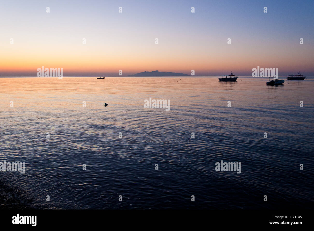 Alba in mare, Kamari, Santorini, Grecia con isola di Anafi a distanza Foto Stock