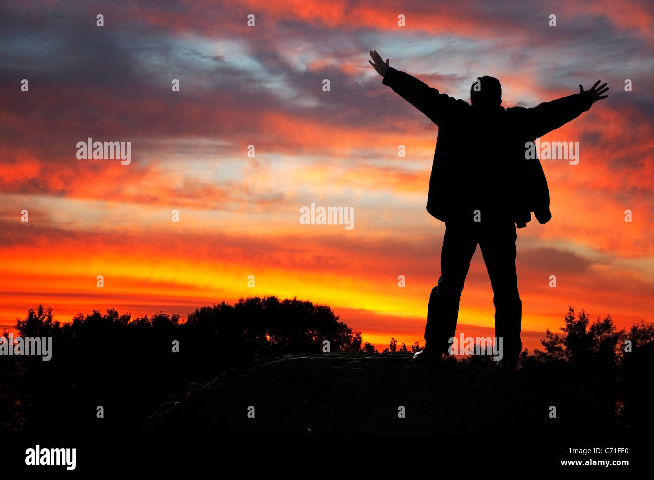 L adorazione del cielo. La silhouette di un uomo con le mani in alto, su un tramonto Foto Stock