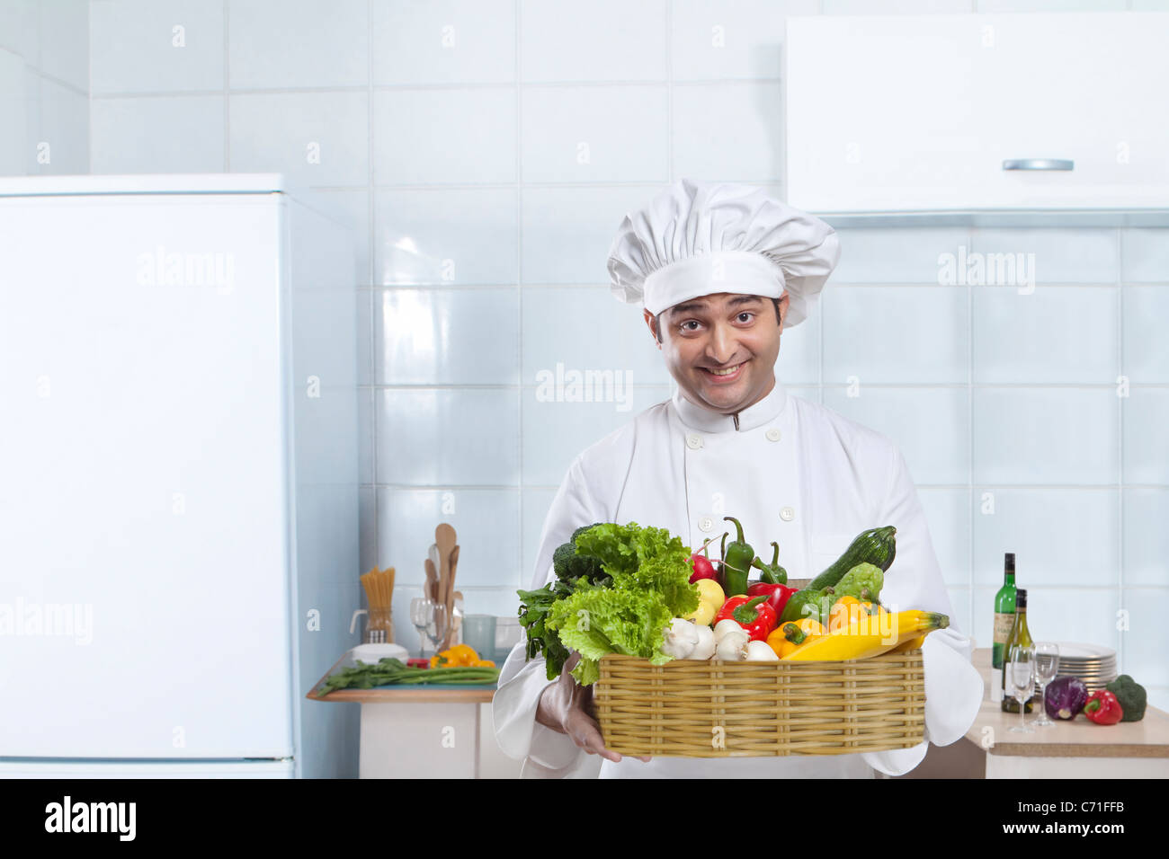 Lo chef che porta un cesto di ortaggi freschi Foto Stock