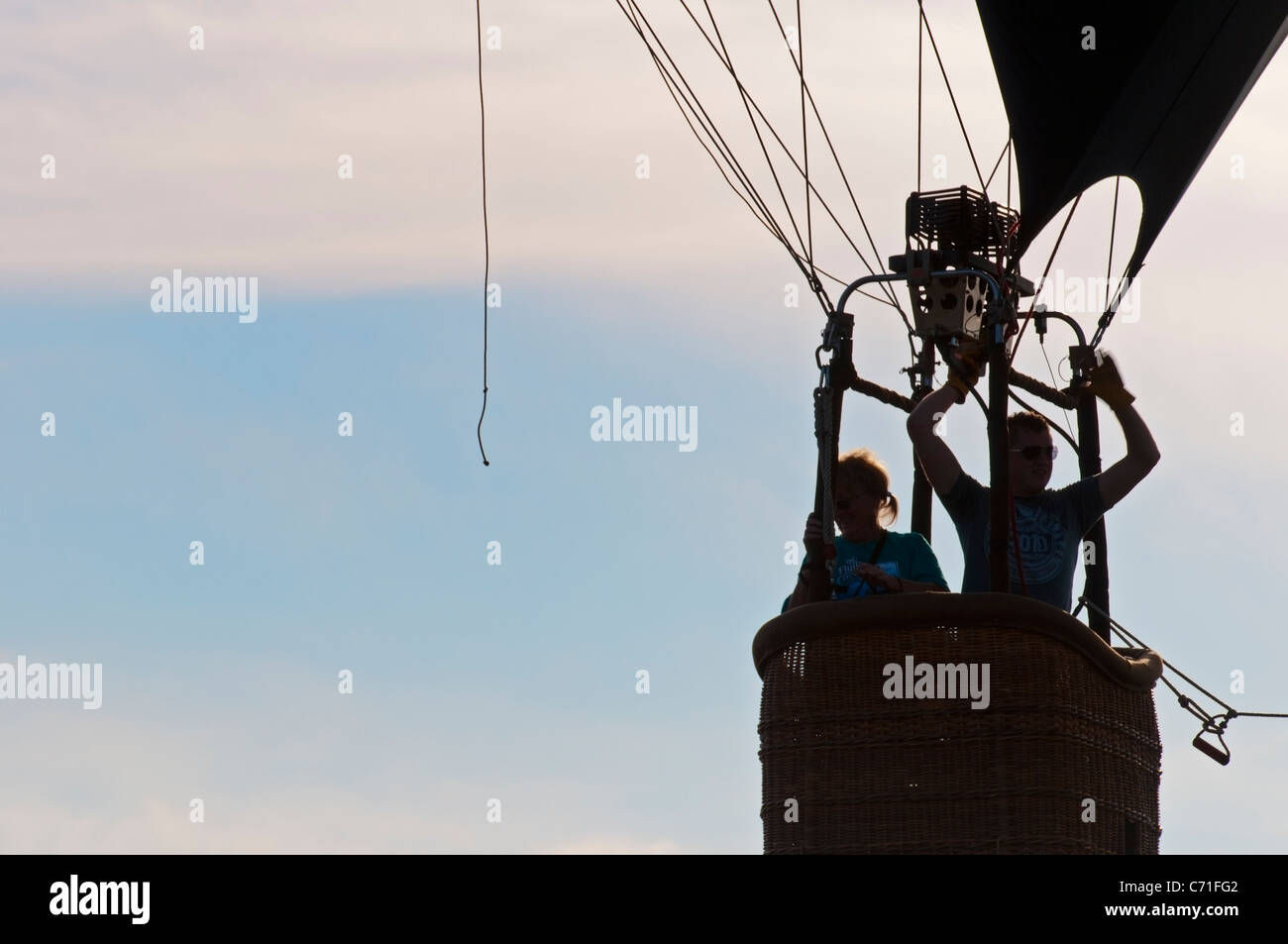 Una mongolfiera con due persone rising profilarsi davanti un nebuloso cielo blu Foto Stock