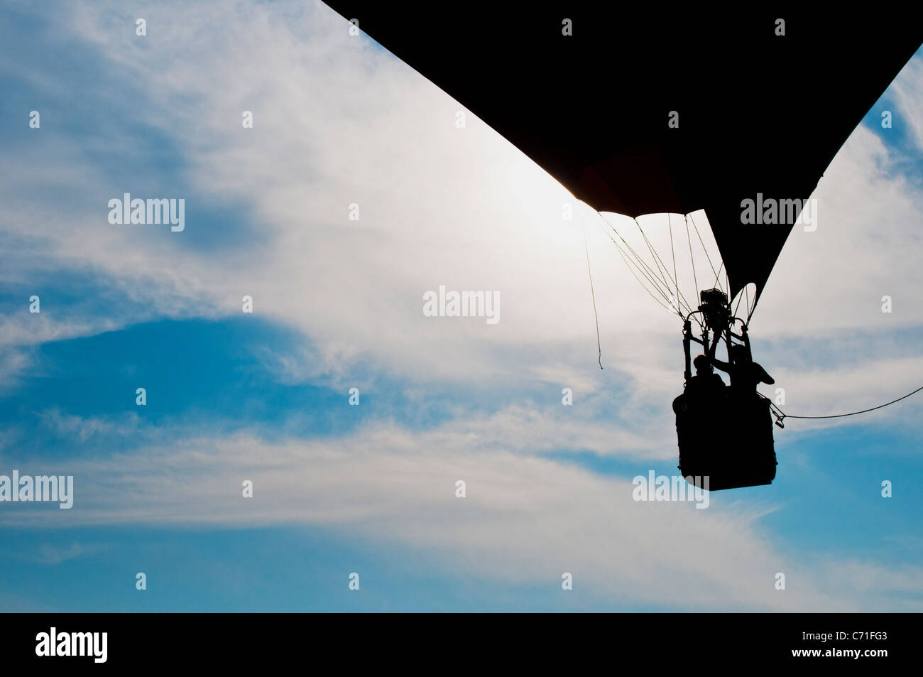 Una mongolfiera con due persone rising profilarsi davanti un nebuloso cielo blu Foto Stock