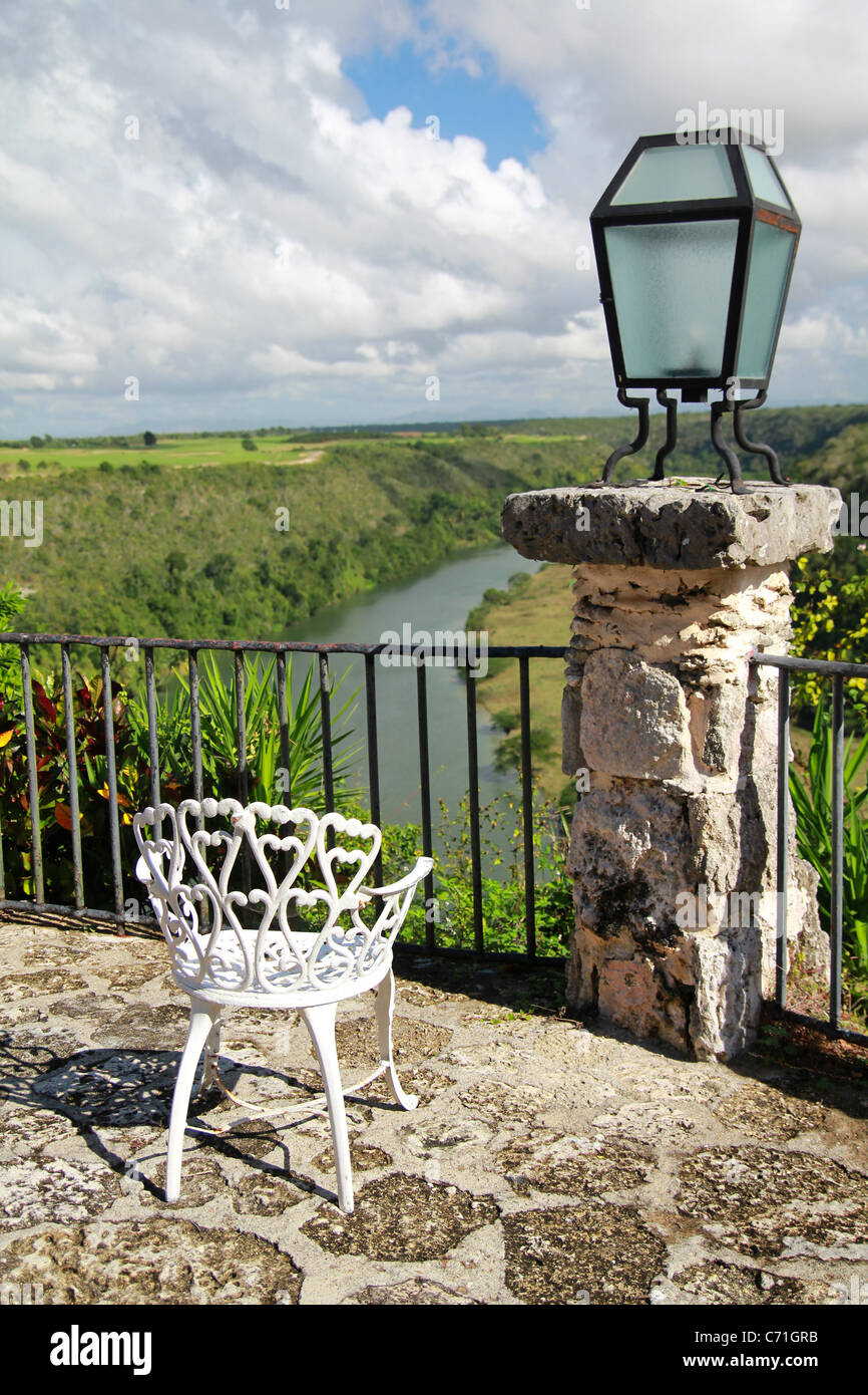 Vecchia sedia in Altos de Chavon cafe con vista sul fiume tropicale Foto Stock