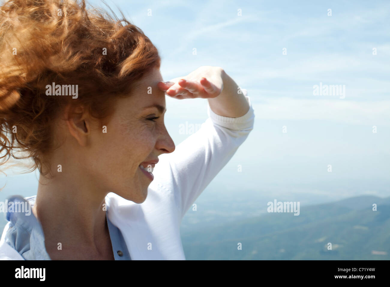 Donna che guarda la vista, ombreggiatura gli occhi con la mano Foto Stock