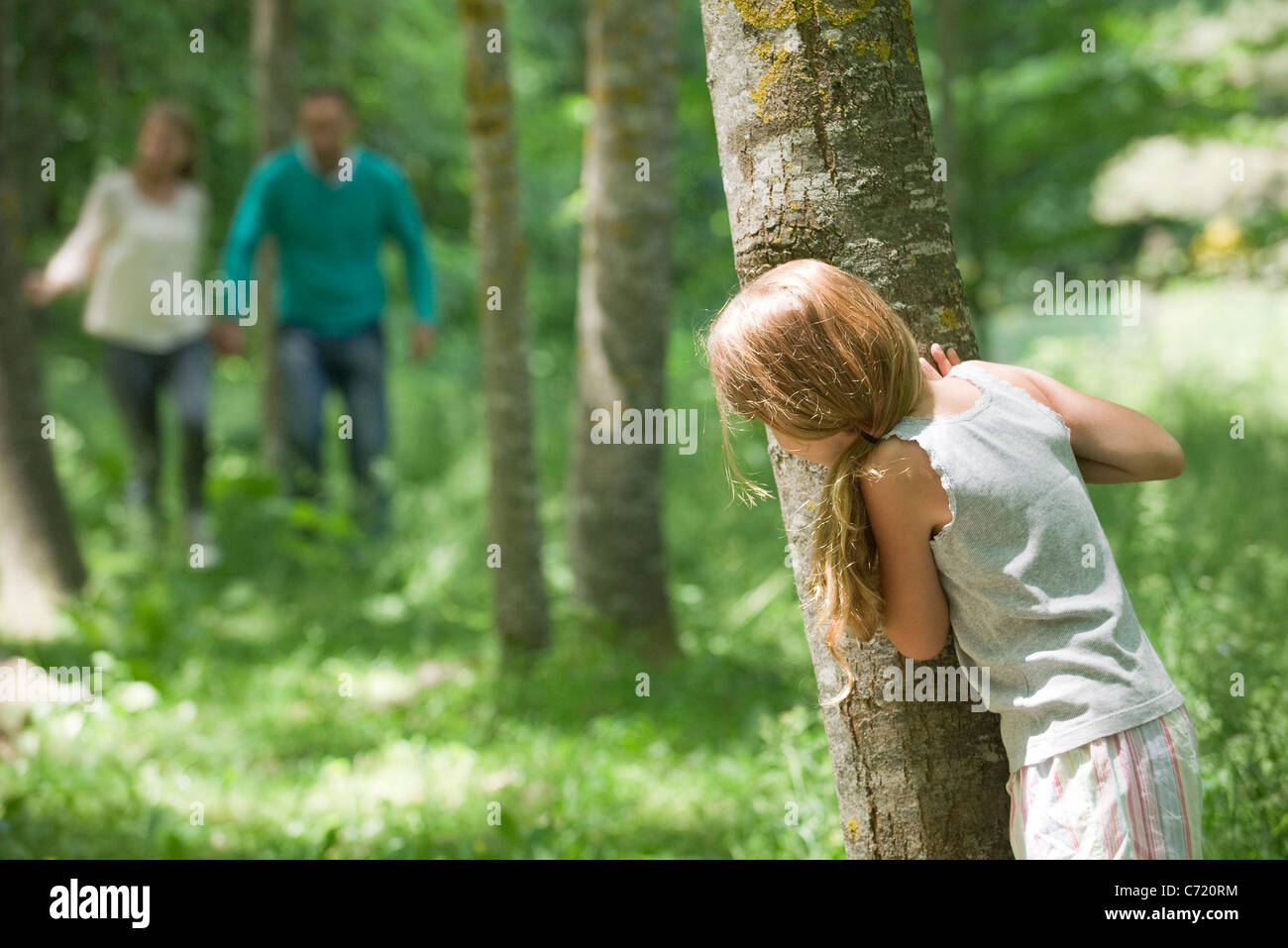 Bambina che si nasconde dietro la struttura ad albero Foto Stock