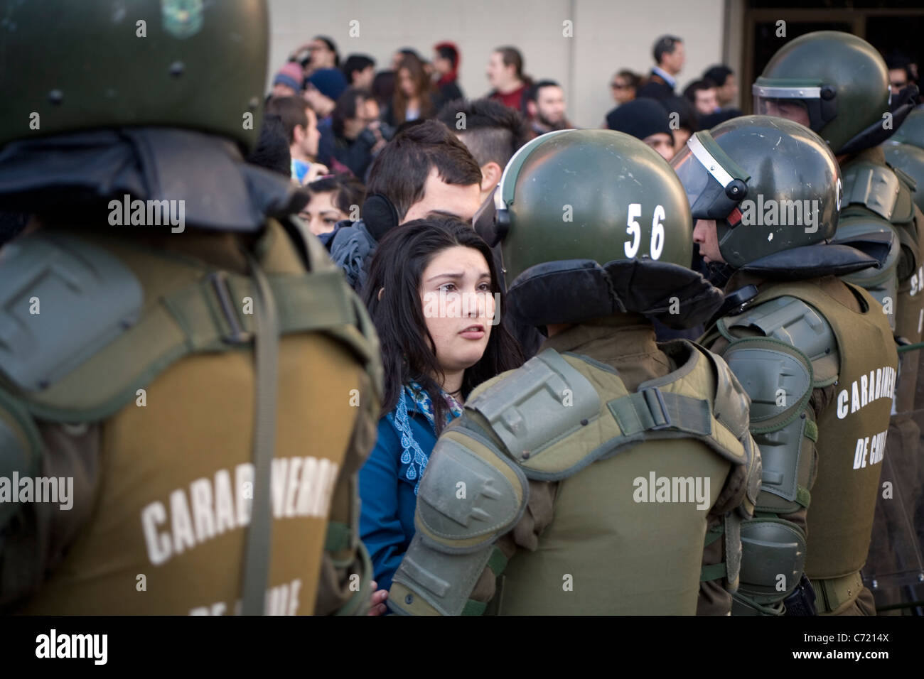 Femmina giovane studente di fronte polizia cilena in piena sommossa ingranaggio, Santiago de Cile Foto Stock