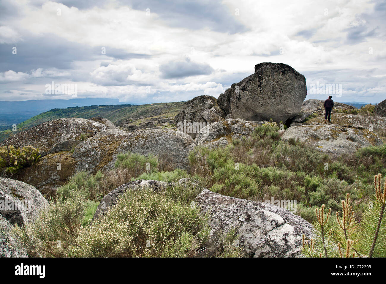 Uomo che cammina nel paesaggio antico di massi scolpiti sulle creste della valle Beira Alta Foto Stock