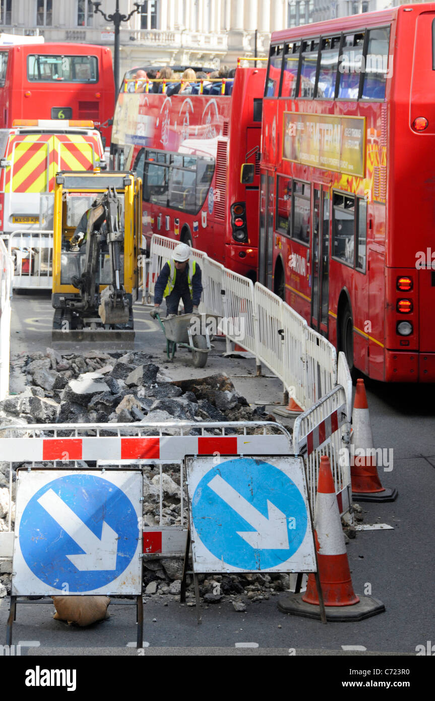 Lavoratori con vista aerea e miniescavatore che lavorano su lavori stradali nella corsia degli autobus accanto al traffico di rosso doppio pianista Autobus Regent Street West End Londra UK Foto Stock