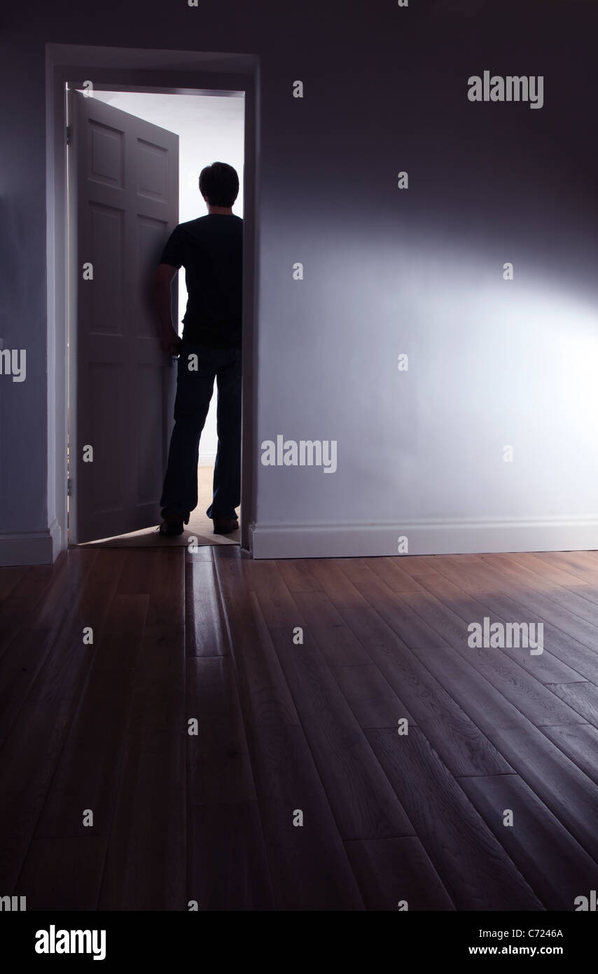 Vista posteriore di un oscuro maschio a piedi di una camera oscura. Foto Stock