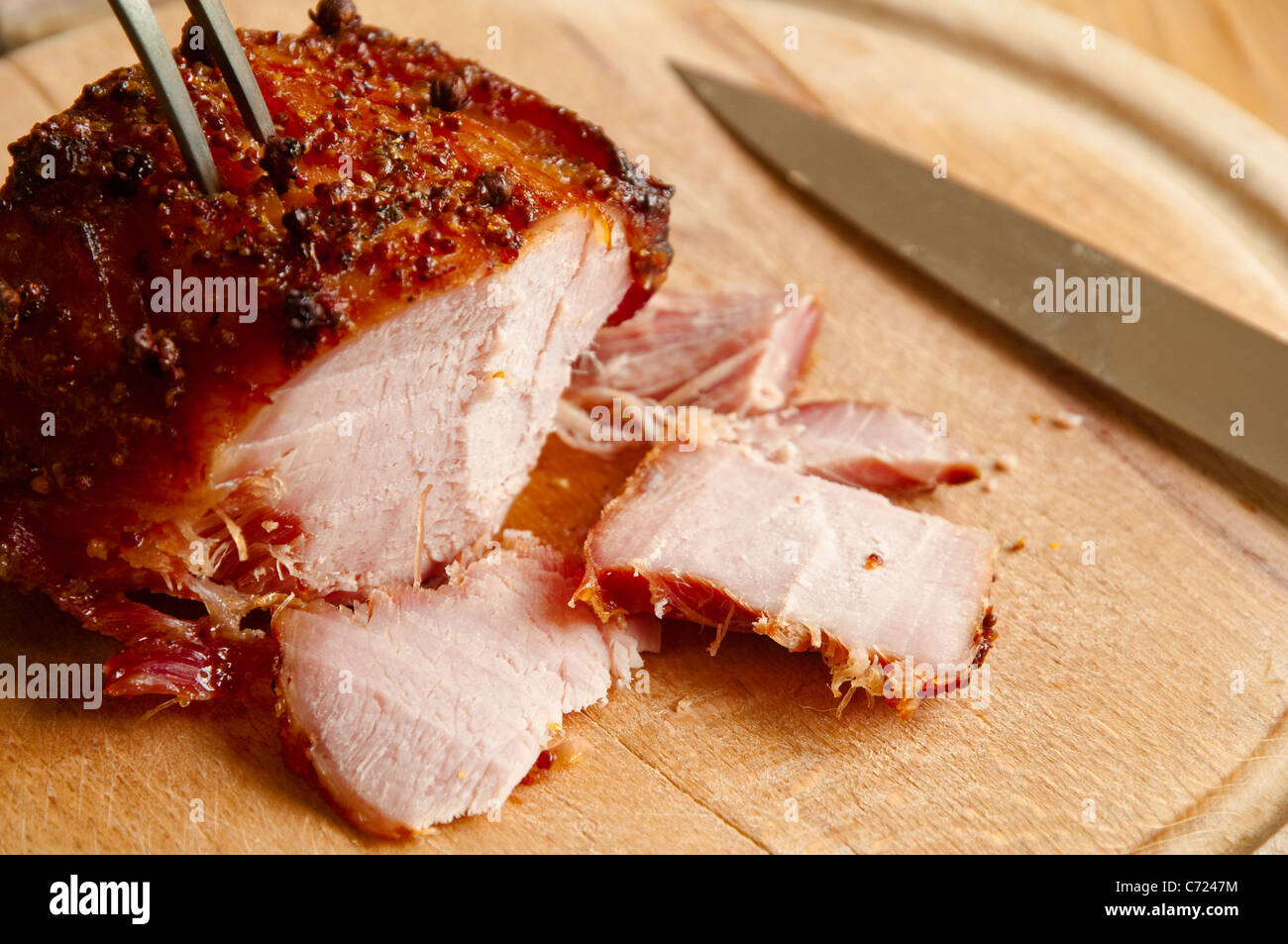 Scolpite di fresco fette di prosciutto arrosto con un miele e senape / smalto di chiodi di garofano - su una tavola di legno. Regno Unito. Foto Stock