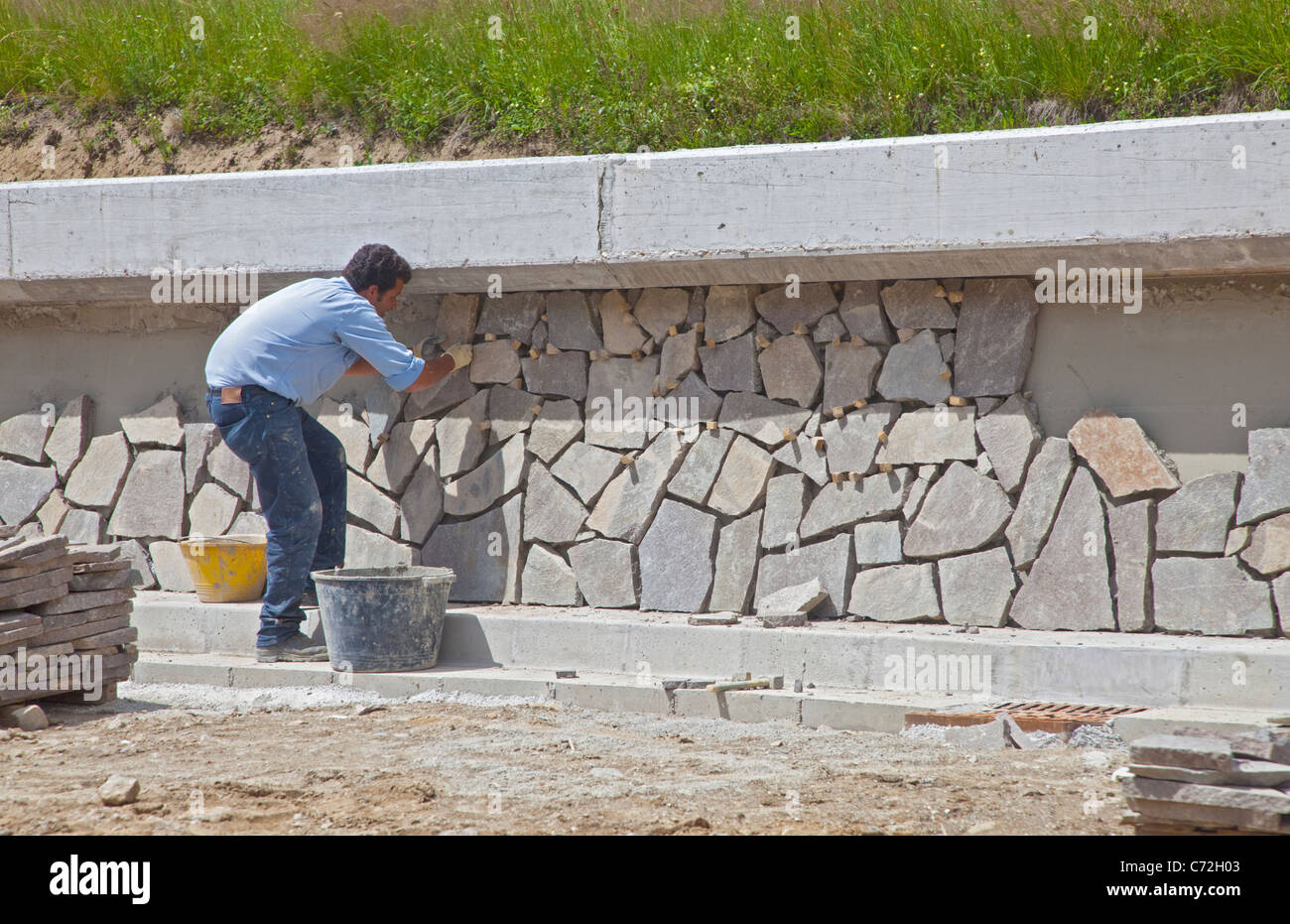 L'uomo la costruzione di muro di pietra lungo la statale, Italia settentrionale Foto Stock