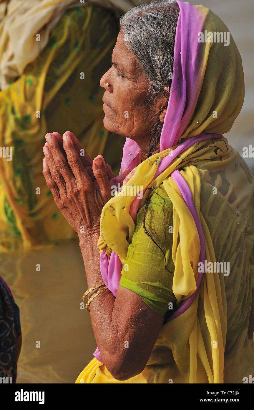 Pellegrino donna la balneazione e di pregare presso il ghat dal fiume Gange. Foto Stock