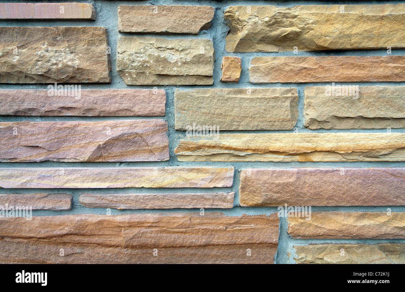 Close-up di colorati in arenaria asimmetriche muro di mattoni Foto Stock