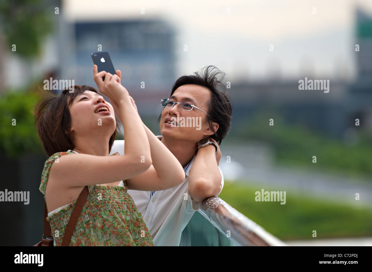 Un giovane cinese matura per scattare delle foto in Hong Kong con un Apple iPhone 4 smartphone. Foto Stock