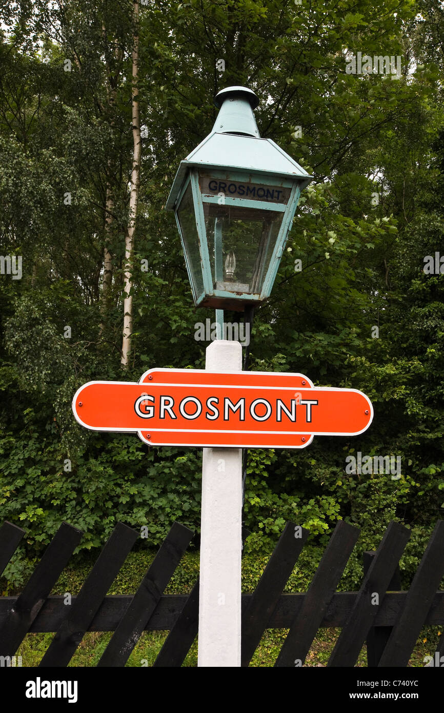 Lampada vecchio post con la stazione ferroviaria di piastra di nome. Grosmont sulla North York Moors Railway. Foto Stock
