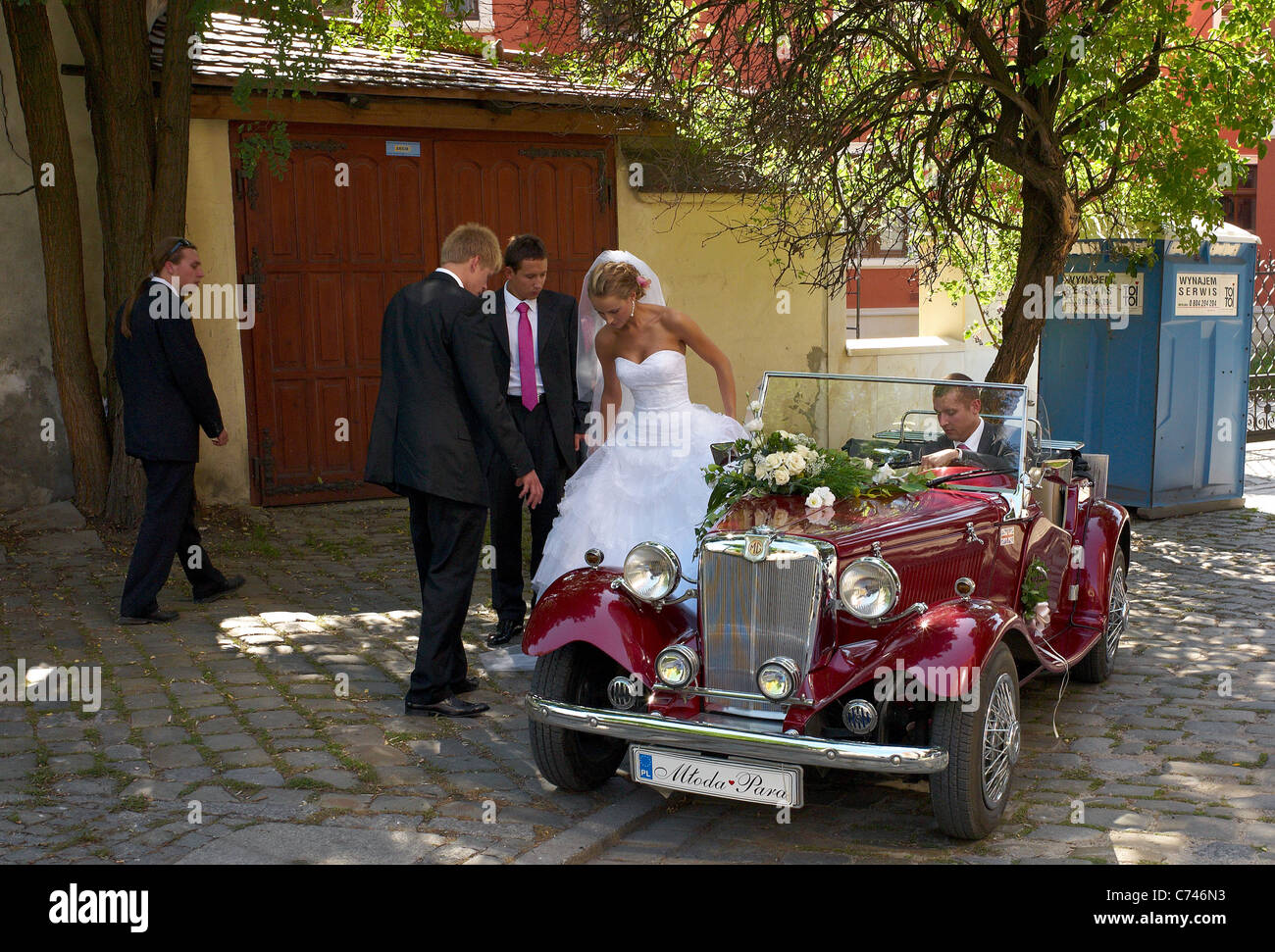 Una coppia di sposi e amici con un MG oldtimer sul Duomo Isola, Wroclaw, Polonia Foto Stock