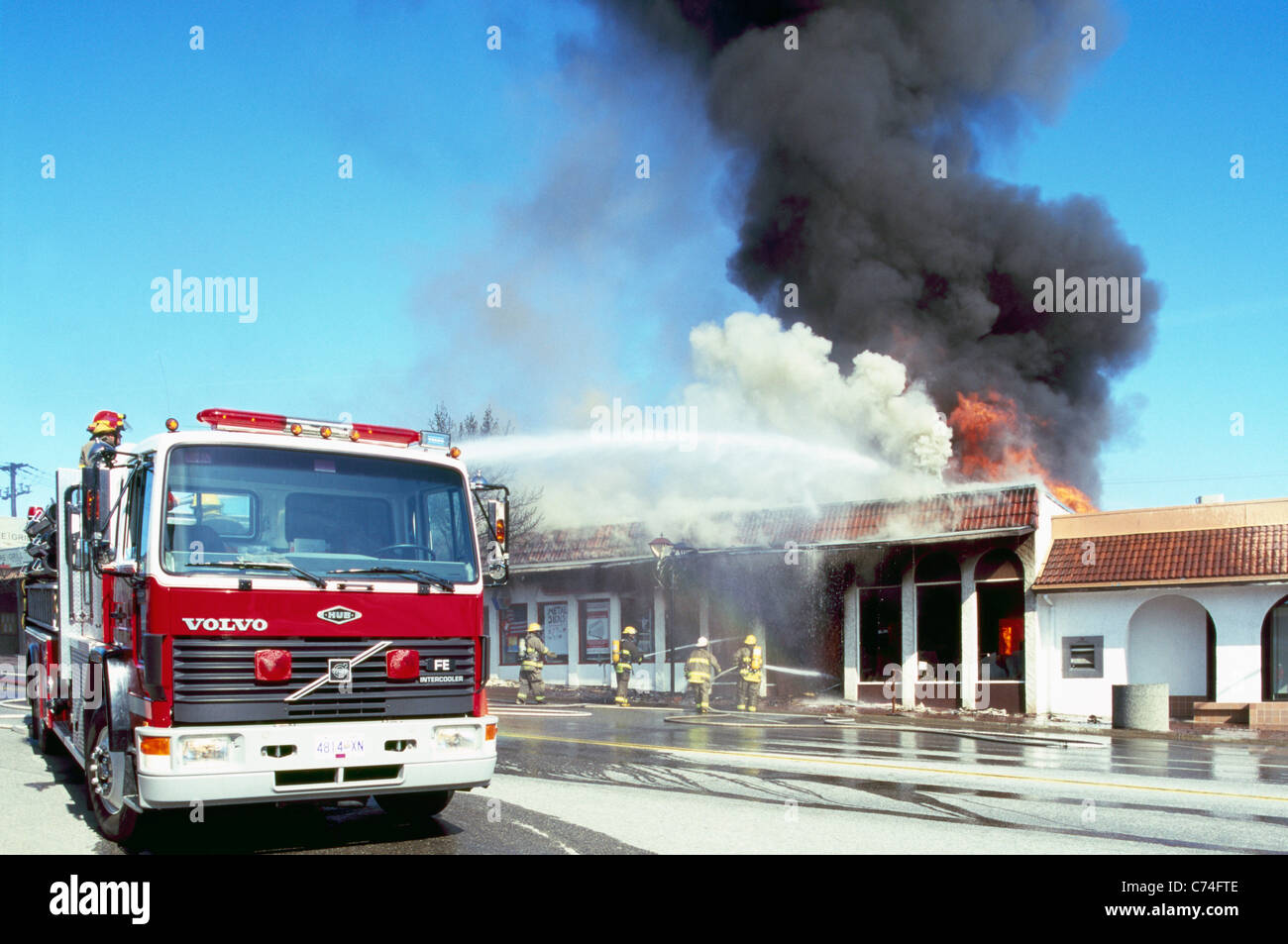 Motore Fire e combattimenti vigili del fuoco fiammeggiante fuoco in combustione edificio con acqua, Osoyoos, BC, British Columbia, Canada Foto Stock