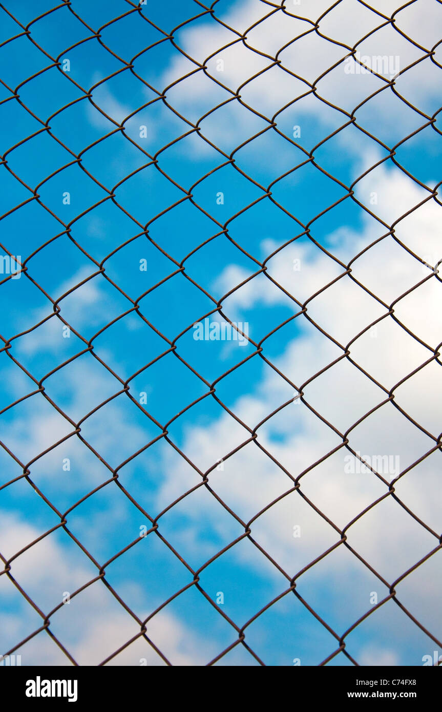 Catena di collegamento cablato grid pattern di recinzione contro il cielo blu. Foto Stock