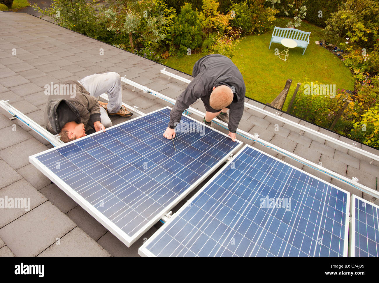 Lavoratori installazione solare pannelli elettrici su un tetto di casa a Ambleside, Regno Unito. Foto Stock