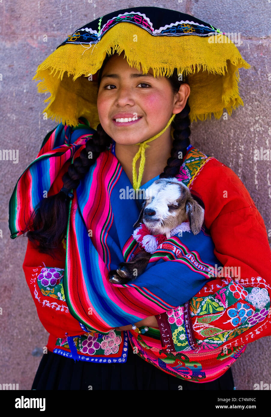 Ragazza peruviana in tradizionali abiti colorati tenendo un agnello in bracci qui Foto Stock