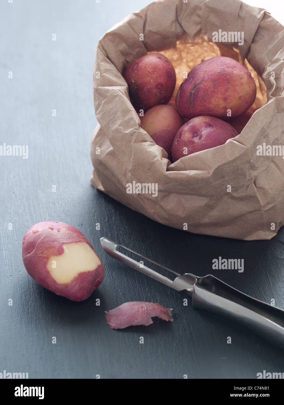 Red baby patate in borsa con sbucciatore e uno parzialmente patata pelata Foto Stock