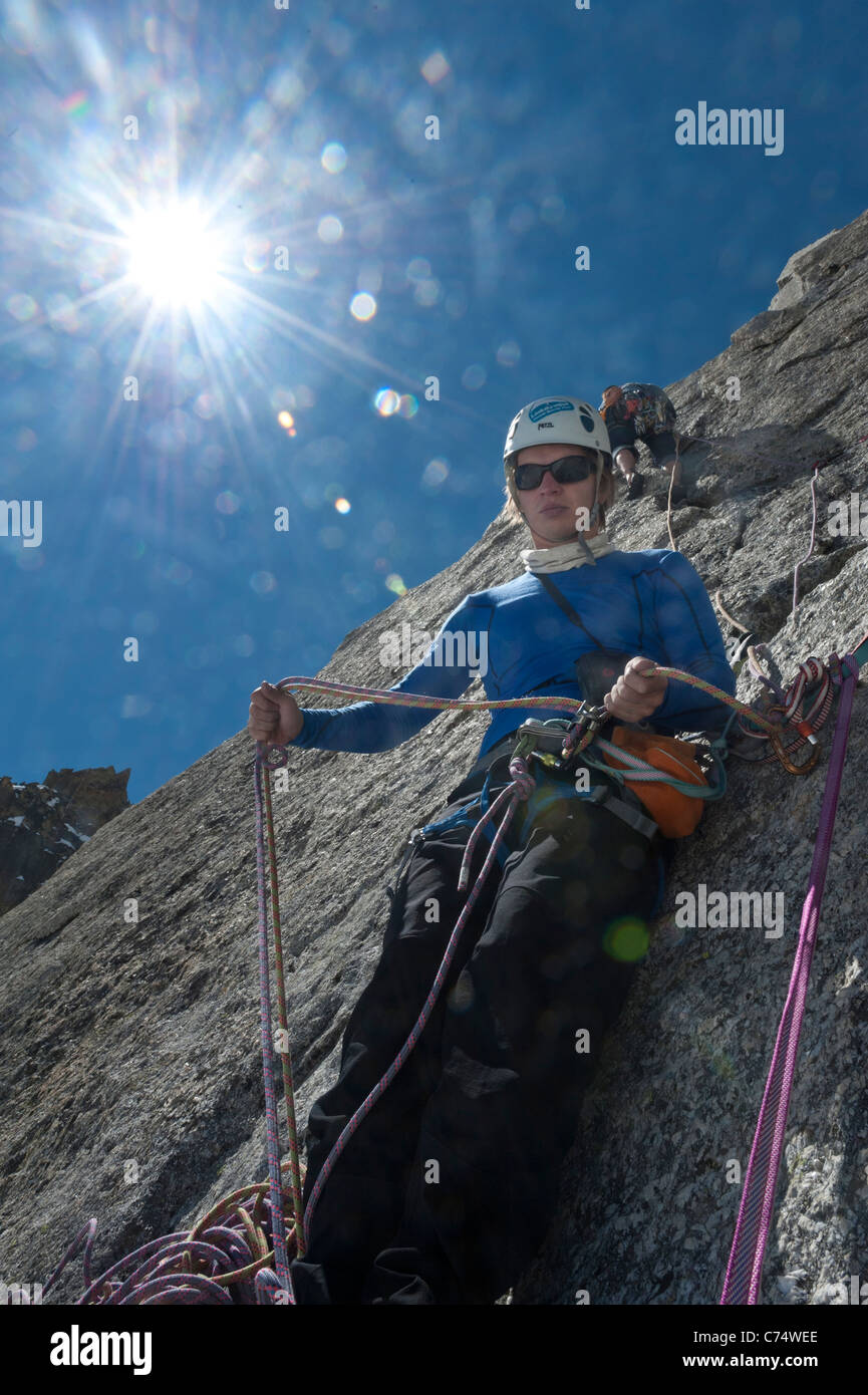 Un belayer belaying il suo partner di arrampicata sul granito di Pyramide du Tacul, Chamonix Mont Blanc. Foto Stock