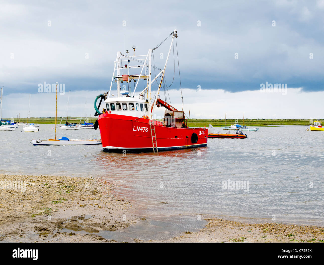 Rosso barca da pesca nel porto di Brancaster Staithe Norfolk in un giorno di pioggia Foto Stock