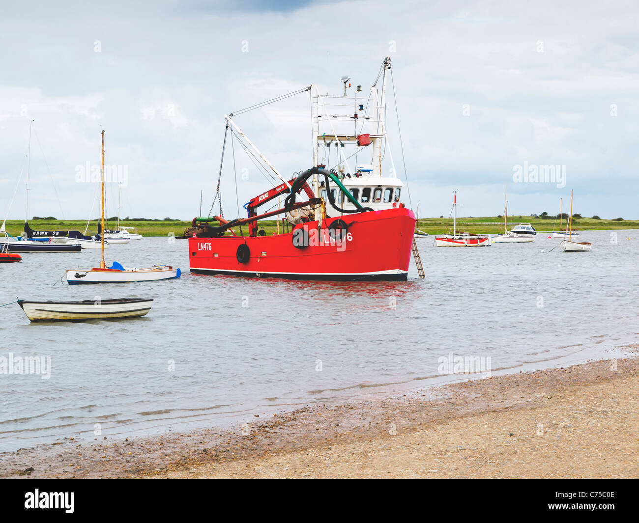 Rosso barca da pesca nel porto di Brancaster Staithe Norfolk in un giorno di pioggia Foto Stock