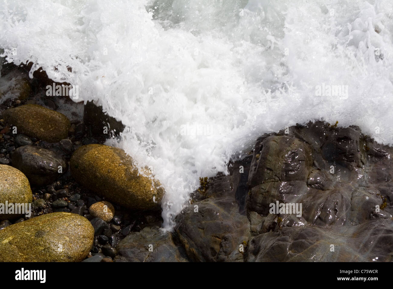 Le pietre a bordo delle acque vengono lavati da una marea Foto Stock