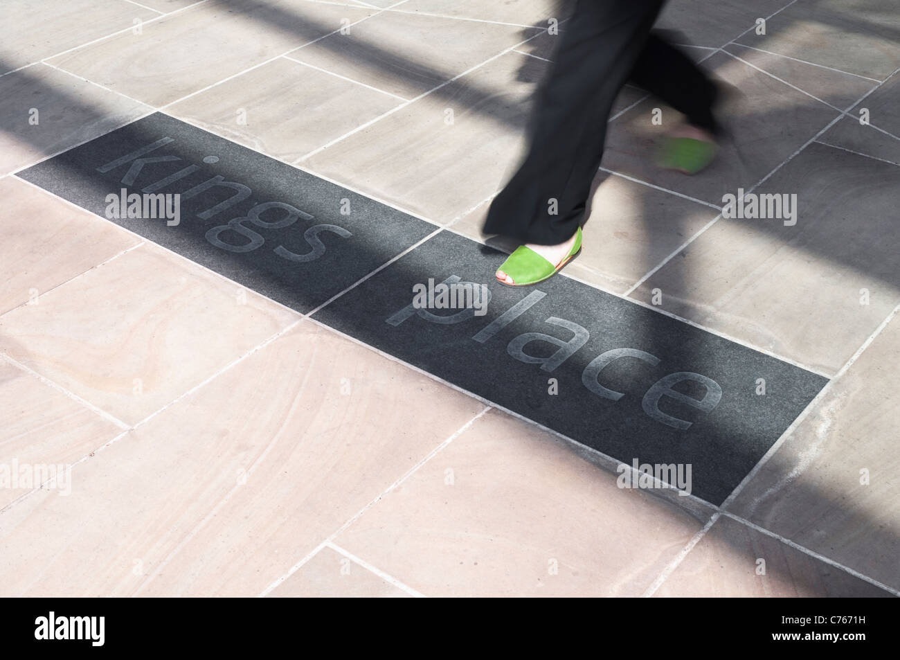 L'ingresso al re luogo a Londra, dotato di piedi sfocate di un passante imprenditrice camminare sopra l'edificio logo. Foto Stock