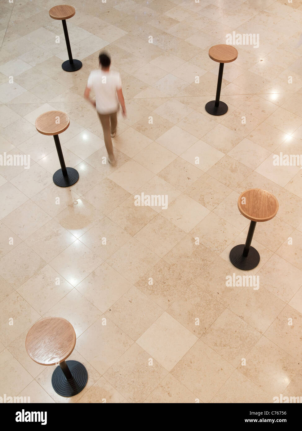 Una vista da sopra di un maschio sfocata a passeggio tra cinque tabelle sul livello di Concerto in re luogo, su York Way, Londra. Foto Stock