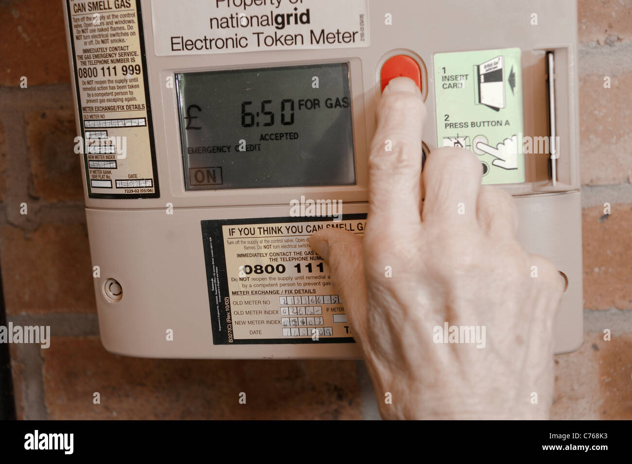 Donna anziana utilizzando una chiave di quantum prepagamento misuratore di gas e il controllo della quantità di credito (sinistra un più costoso di pagamento) Foto Stock