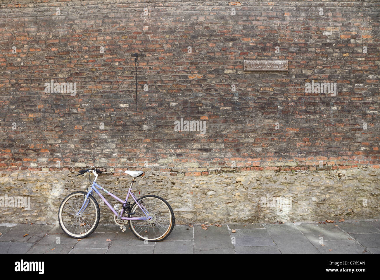 Non sporgersi biciclette contro questa parete bike appoggiata sulla parete Foto Stock