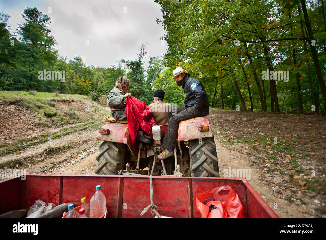 Famiglia contadina in un trattore con un rimorchio di andare a lavorare sul campo, fresatrici Foto Stock