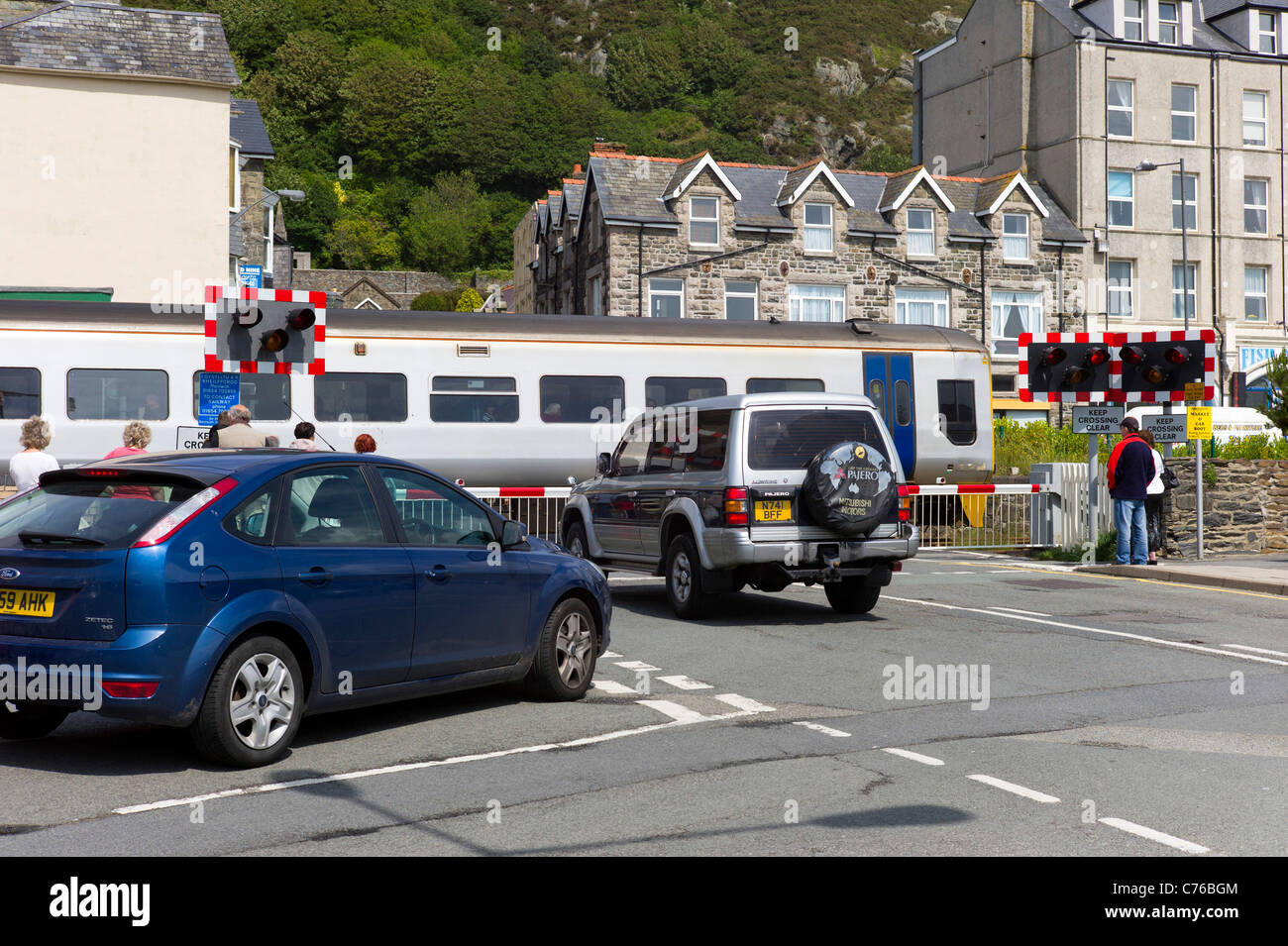 Un treno è utilizzando un passaggio a livello Beach Road vicino al centro della città di Barmouth, il Galles del Nord. Pedoni e automobili attendono l'apertura. Foto Stock