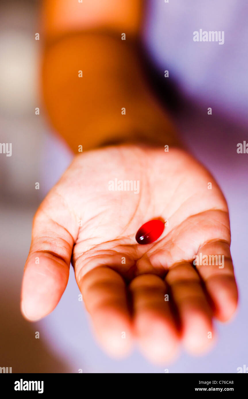 Pillola a portata di mano, una pastiglia rossa viene consegnato da una donna. Foto Stock