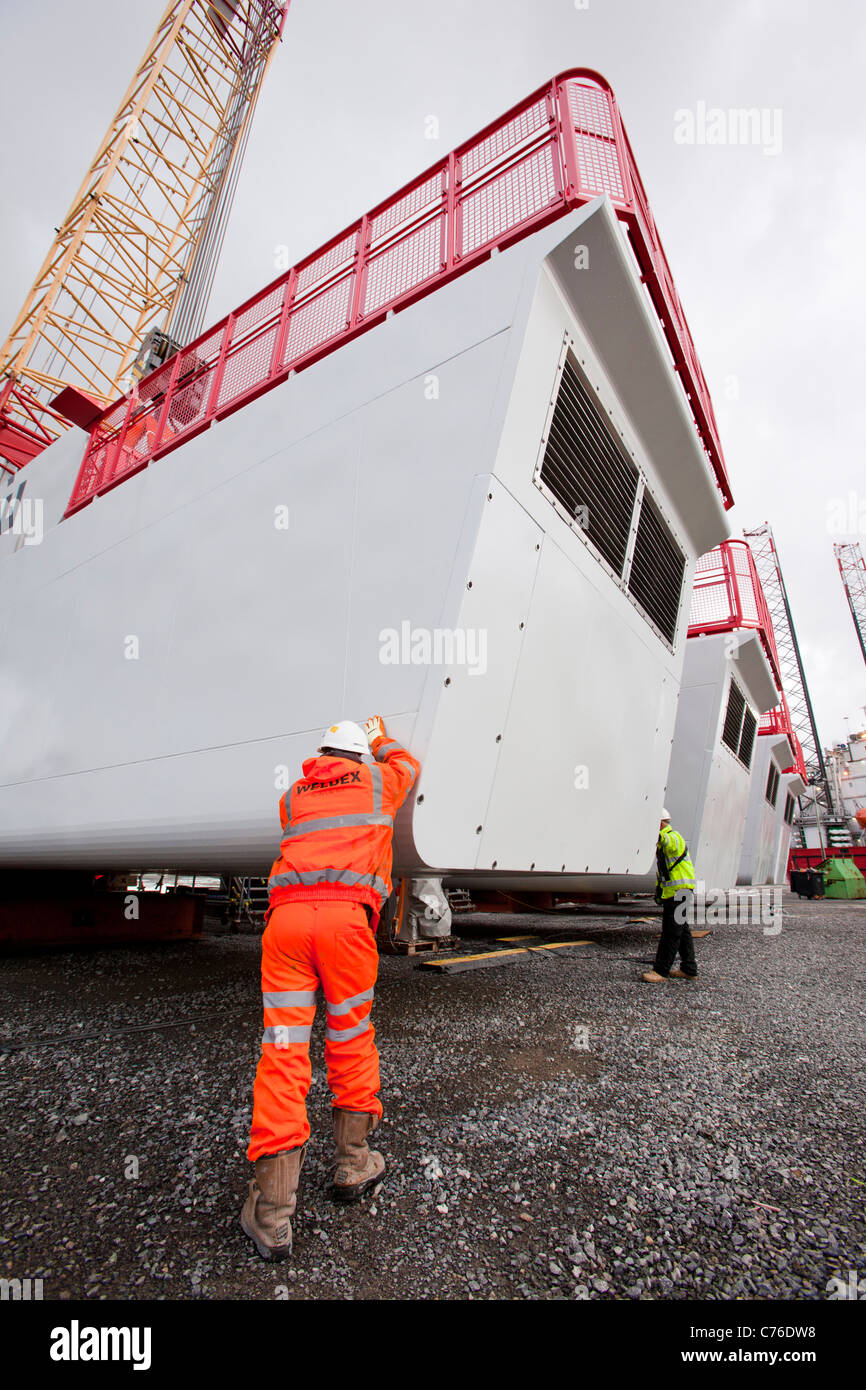 I lavoratori di sollevare una navicella per una turbina eolica su un martinetto fino chiatta, per il Walney offshore wind farm. Foto Stock