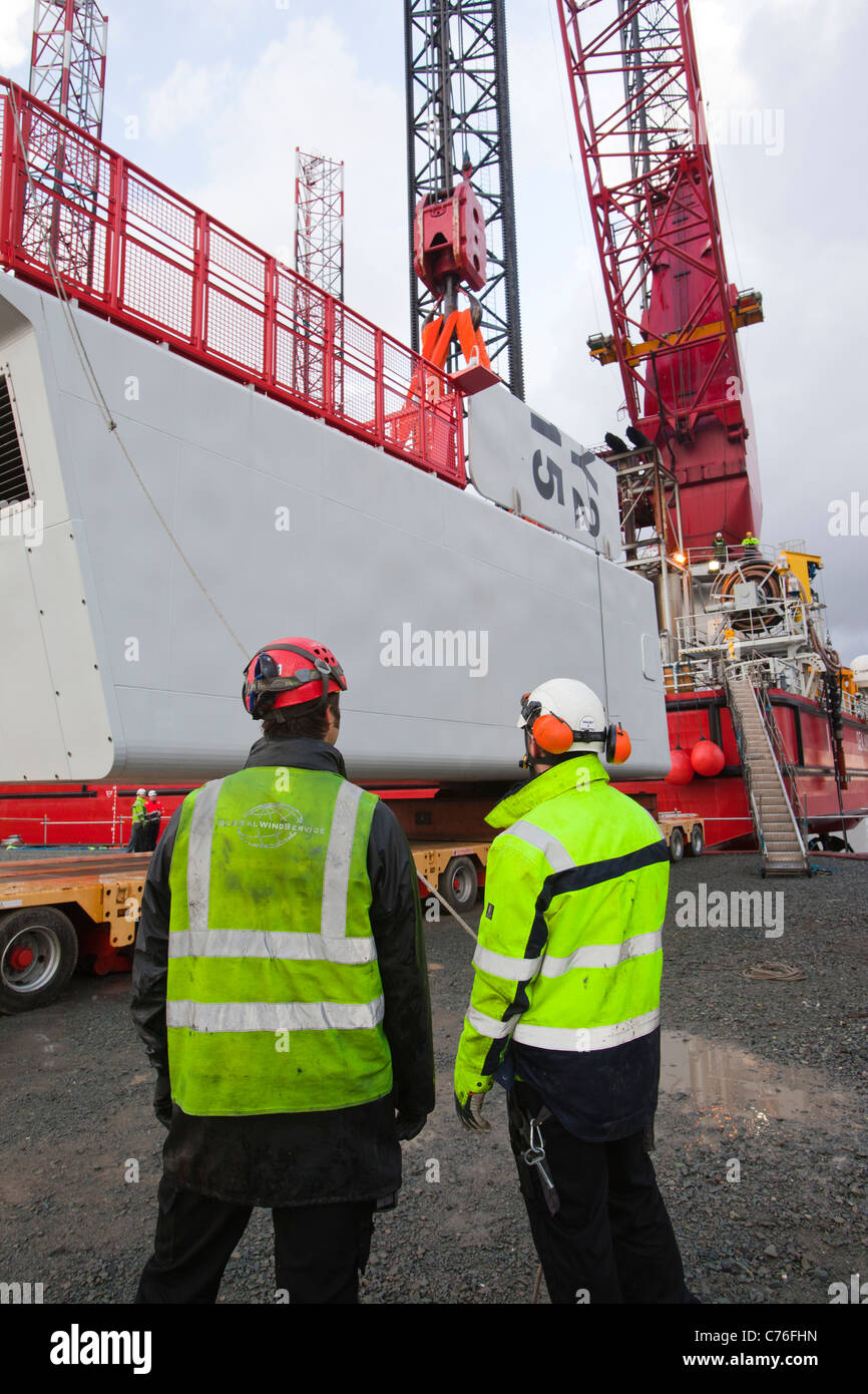 I lavoratori di sollevare una navicella per una turbina eolica su un martinetto fino chiatta, per il Walney offshore wind farm. Foto Stock