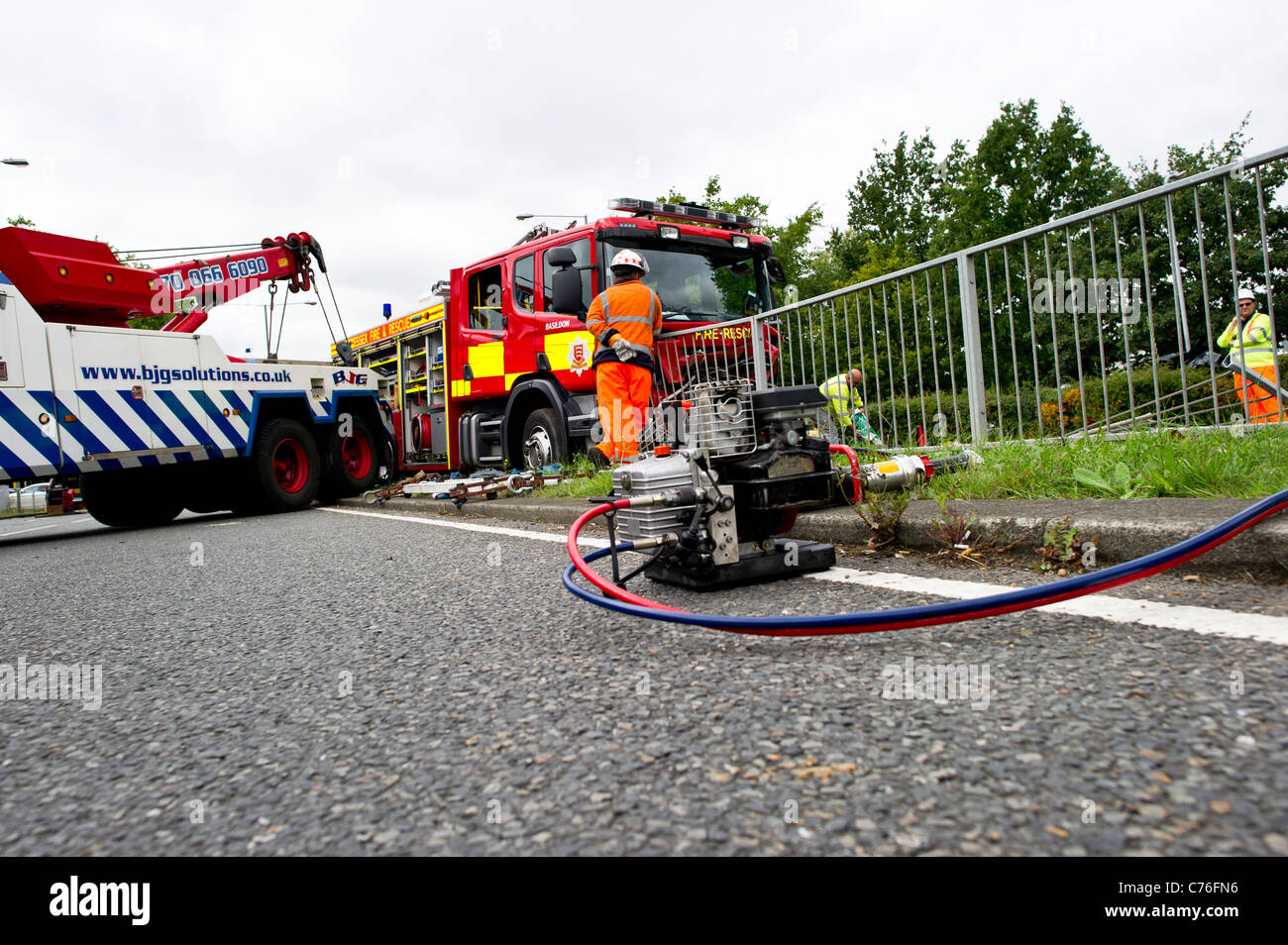 Lavoratori di recupero preparazione per cancellare la scena di un grave incidente stradale che coinvolge un incendio del motore e di un'auto. Foto Stock