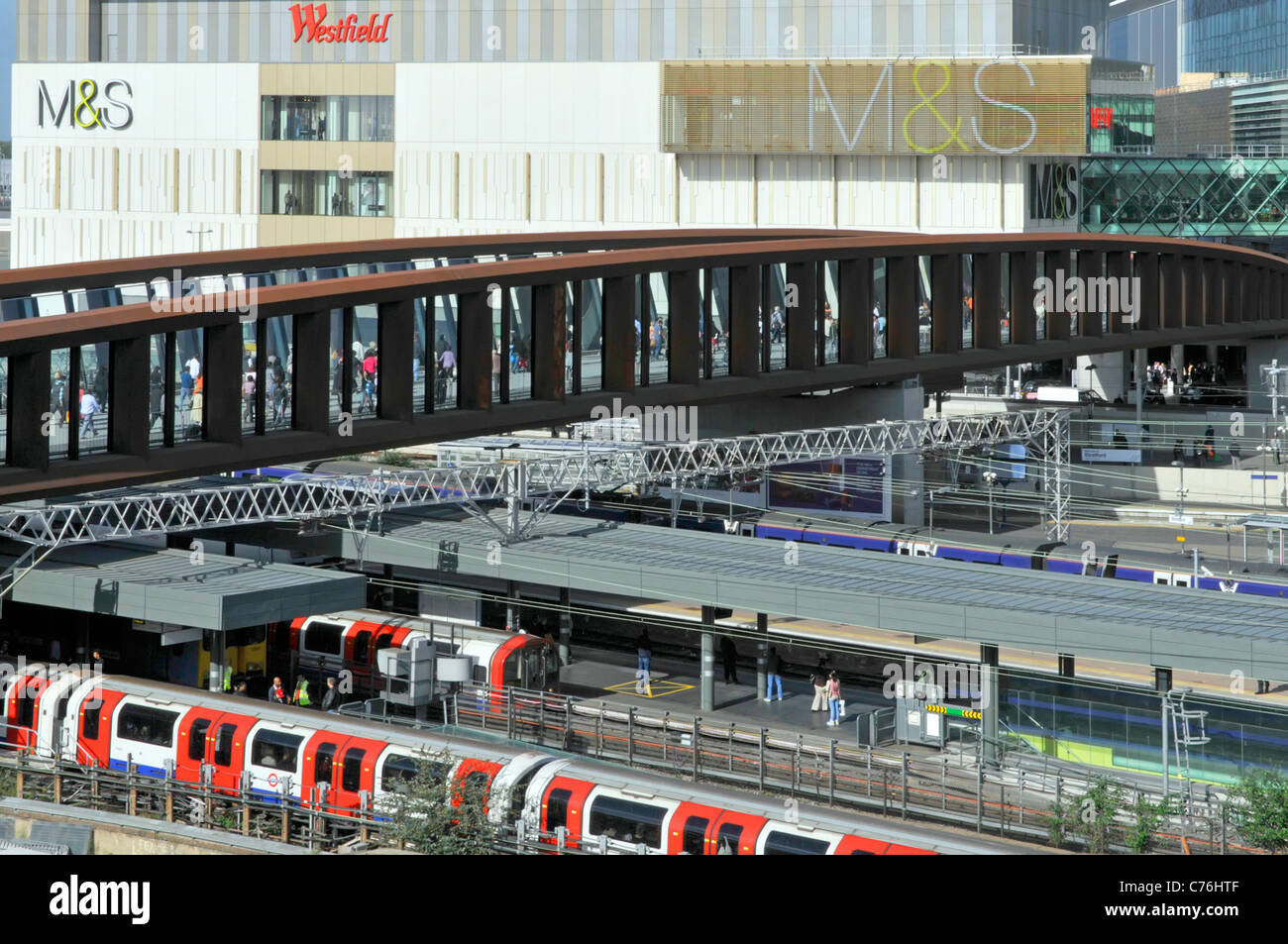 Ponte d'ingresso del centro commerciale Westfield e treno della metropolitana con vista aerea Al binario della stazione di Stratford, M&S, sign su Marks e Spencer Building East London UK Foto Stock