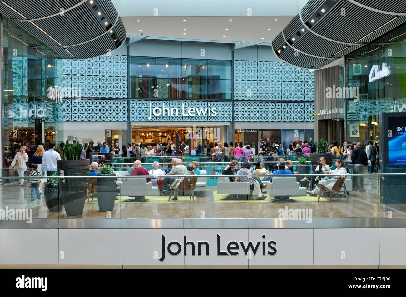 Persone seduti all'interno del centro commerciale all'ingresso di John Lewis Grandi magazzini presso il centro commerciale Westfield Stratford City East London Inghilterra Regno Unito Foto Stock