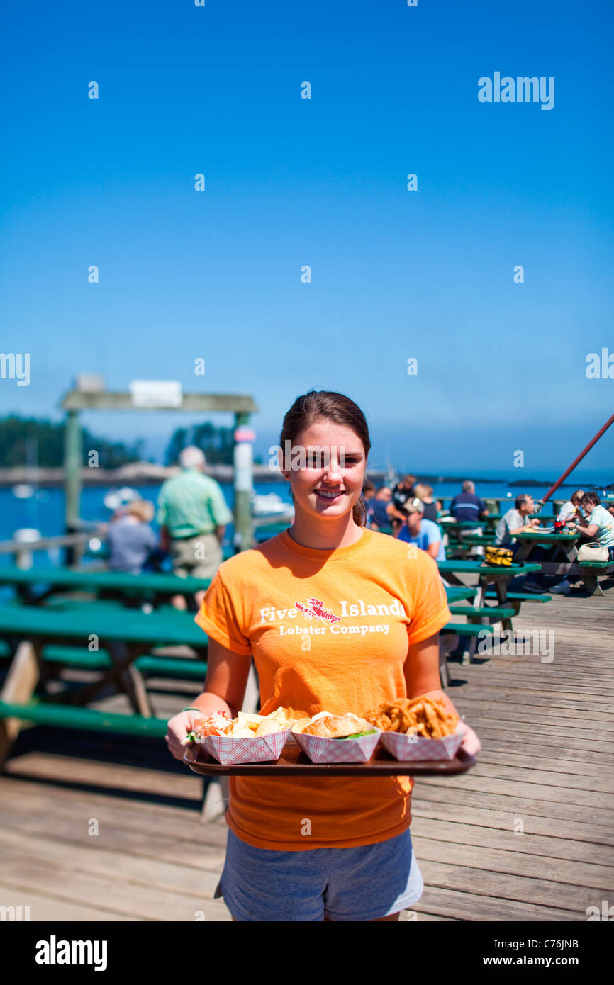 Un server può contenere un piatto di frutti di mare su una dock in un pomeriggio soleggiato. Foto Stock