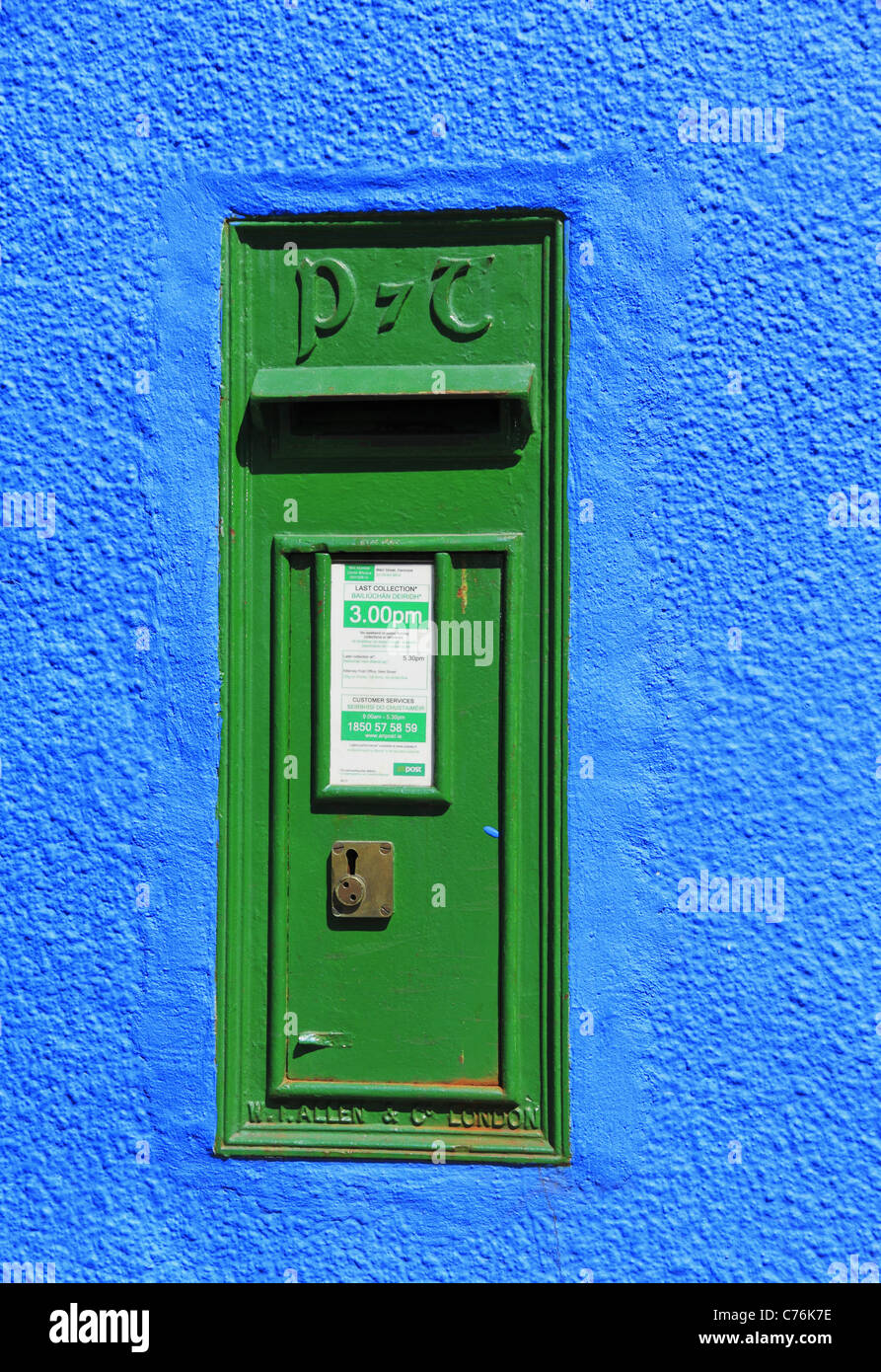 Un dipinto luminosamente muro di casa ospita un servizio postale irlandese casella postale, Kenmare, Co Kerry, Rep dell'Irlanda. Foto Stock