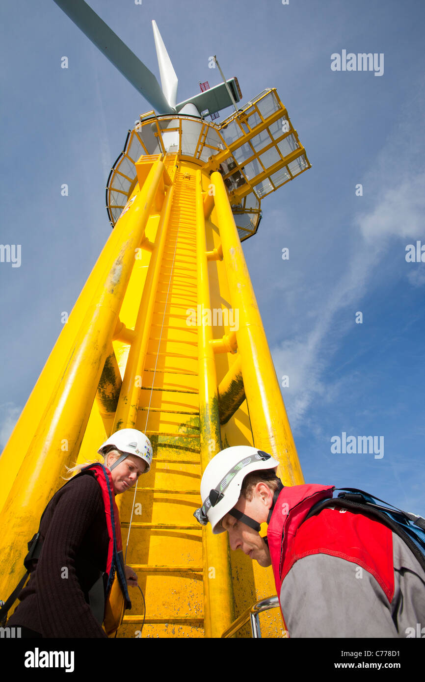 Un operaio si arrampica su una turbina eolica in Walney offshore wind farm. Foto Stock