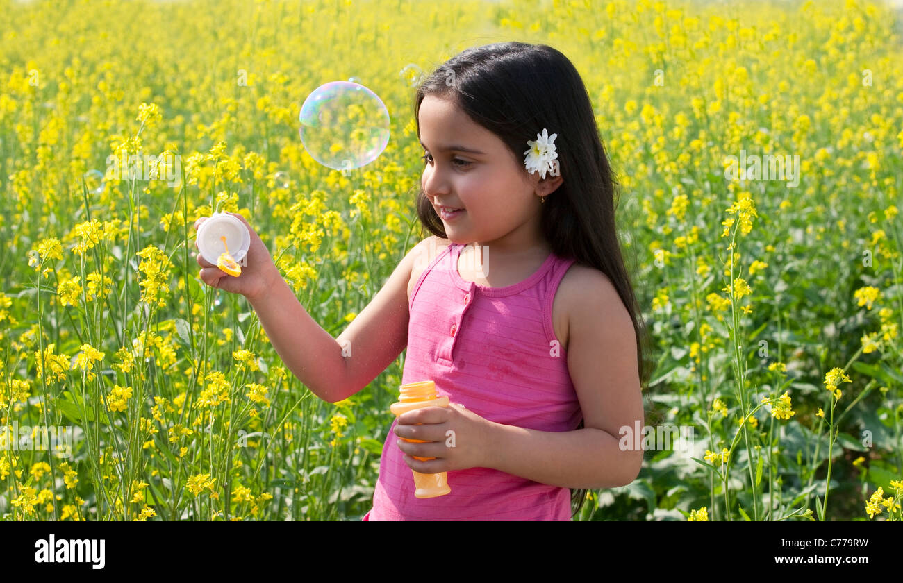 Ragazza giovane rendendo le bolle in un campo Foto Stock