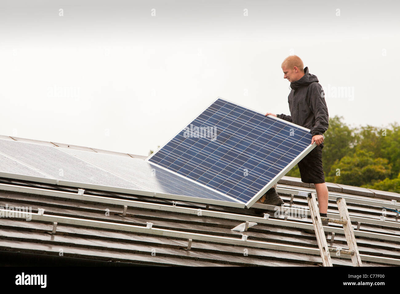 Lavoratori un raccordo 4 Kw sistema di pannelli solari per una casa tetto in ambleside, cumbria, Regno Unito. Foto Stock
