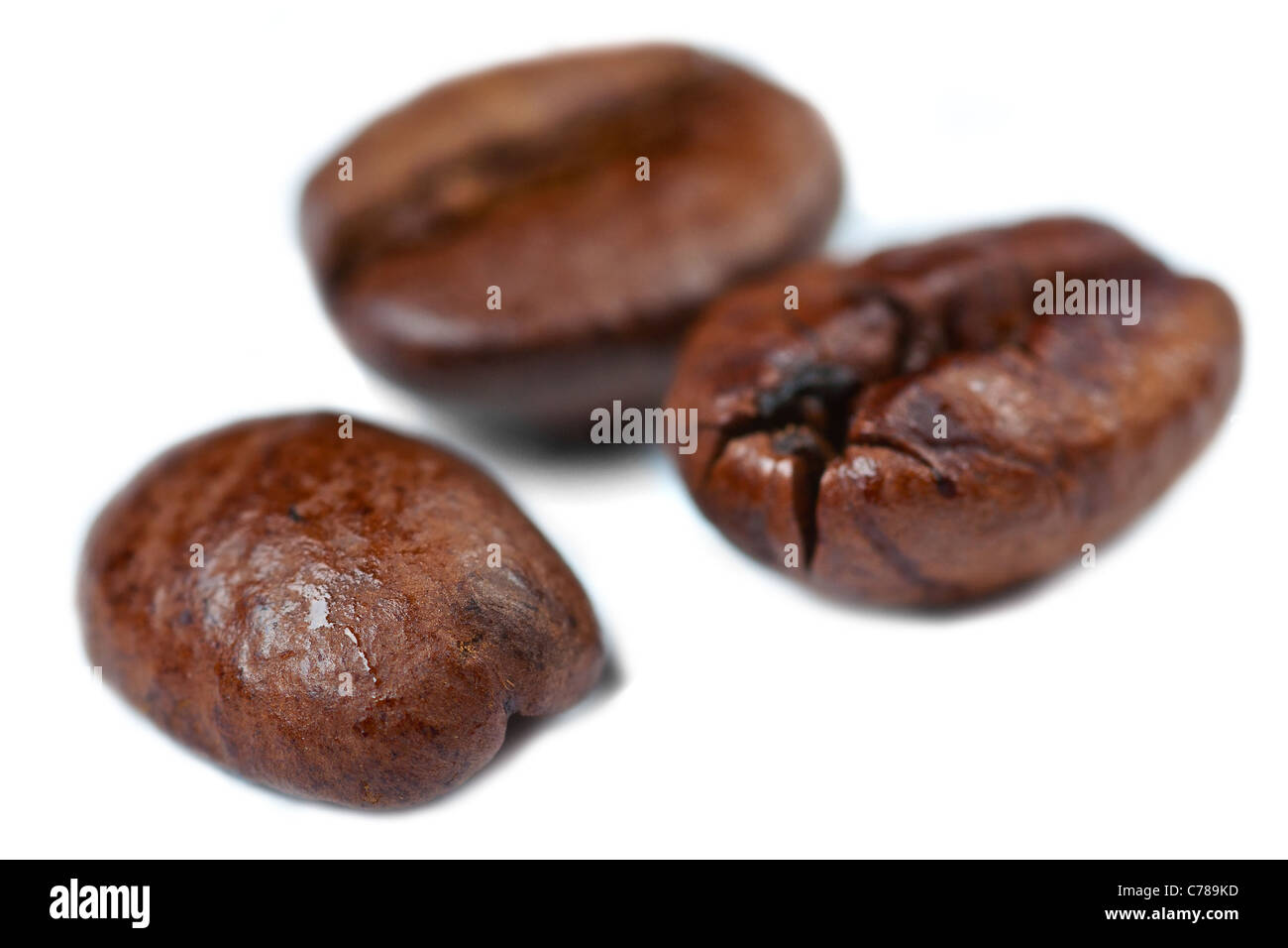 Tre chicchi di caffè su uno sfondo bianco con bassa profondità di campo. Foto Stock