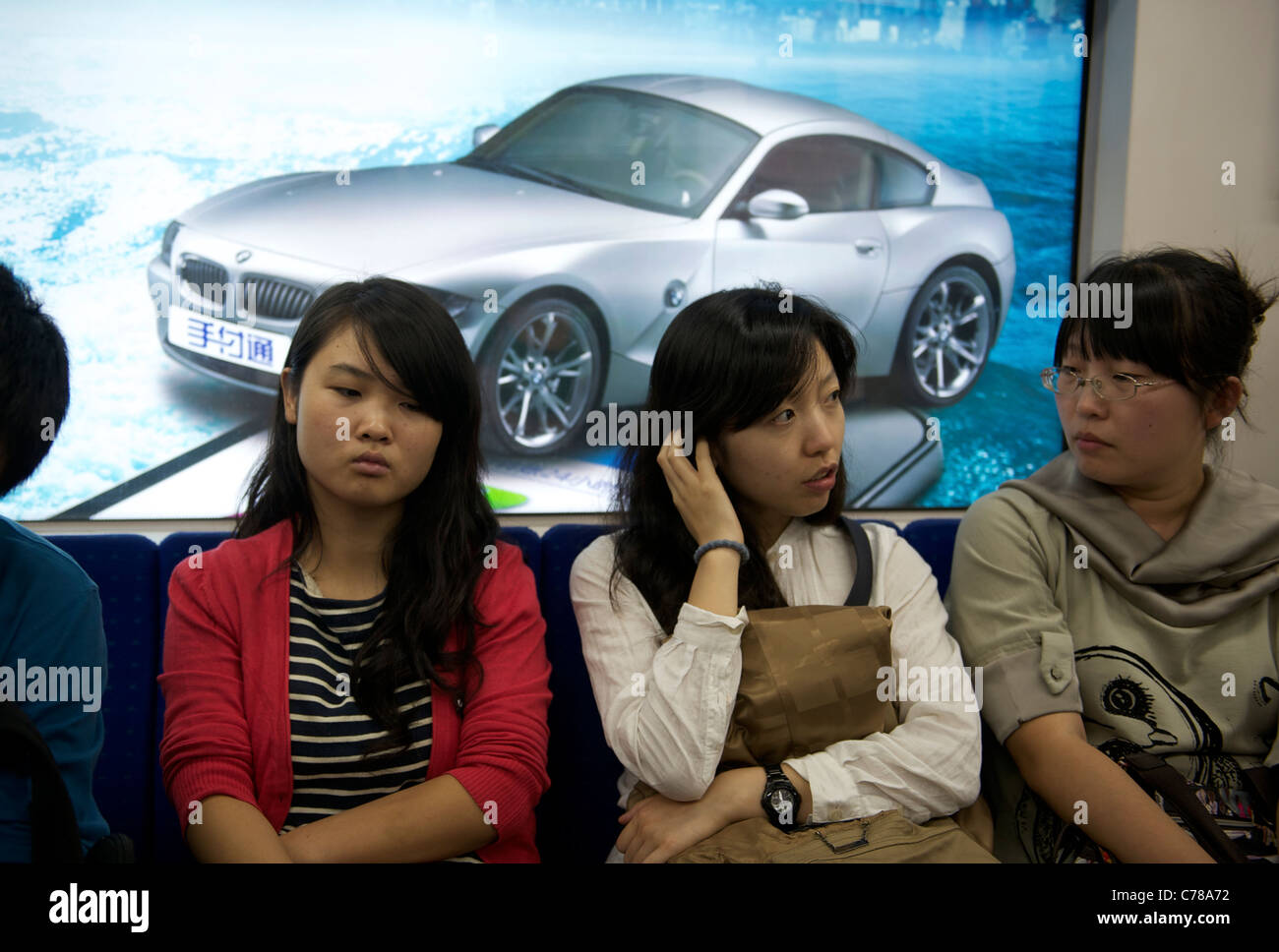 Le donne cinesi di sedersi di fronte un tabellone auto sul tubo a Pechino in Cina. 11-set-2011 Foto Stock
