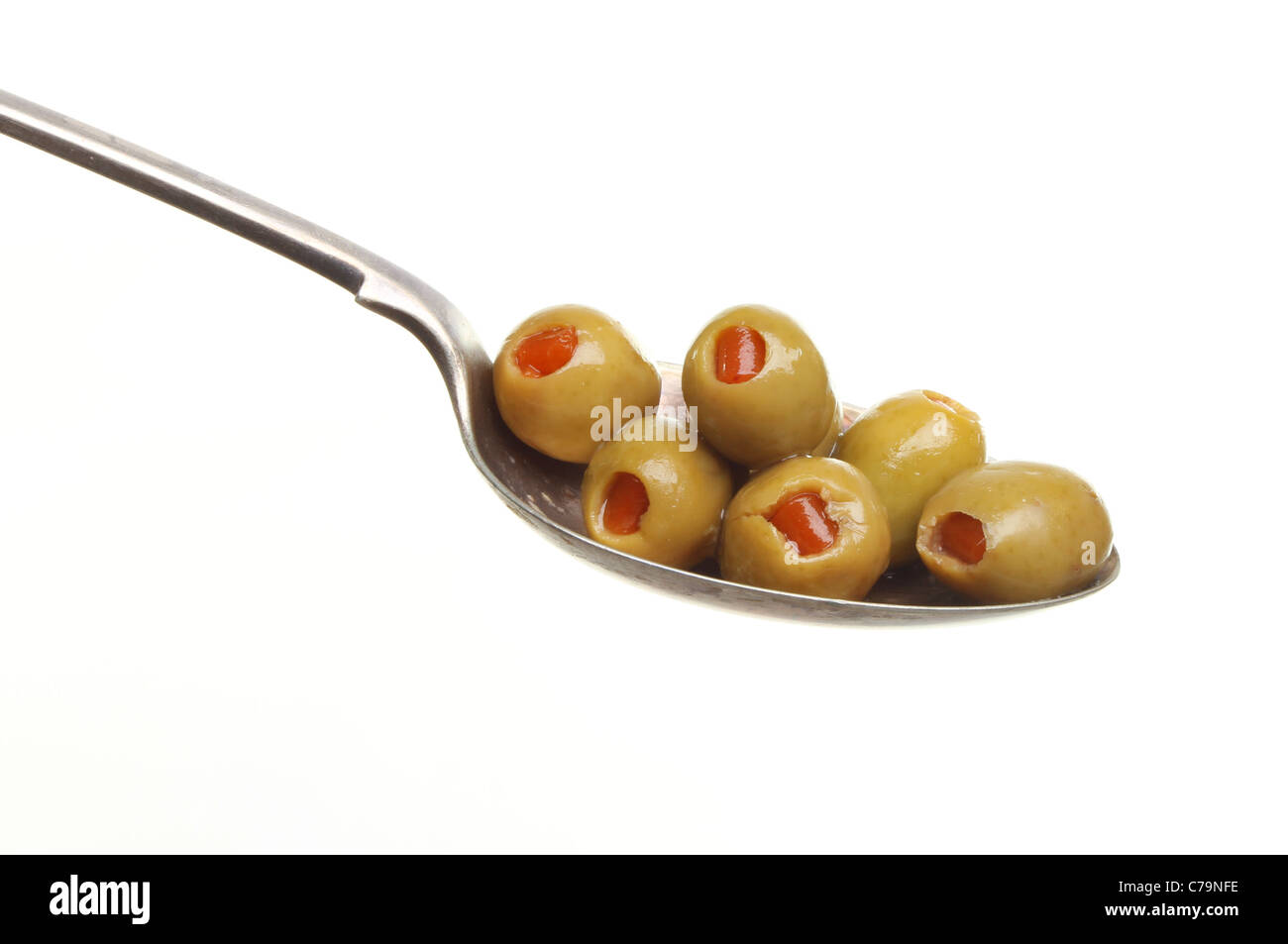 Il pimento Olive farcite in un cucchiaio d'argento isolato contro bianco Foto Stock